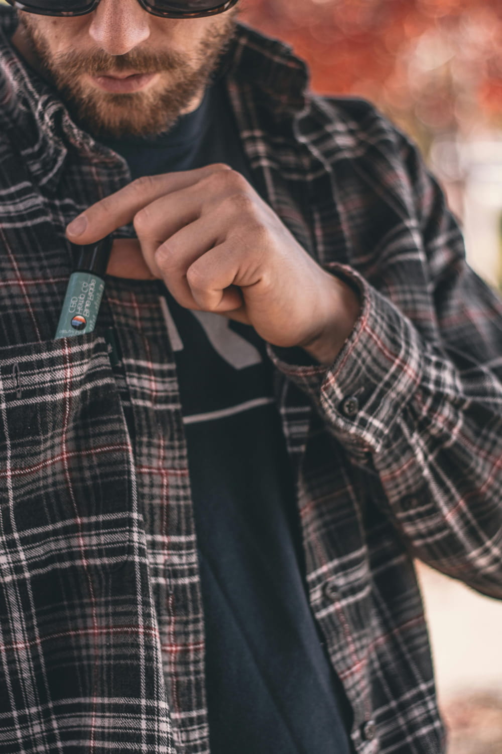 Ein Mann im Karohemd verstaut diskret ein CBD Produkt in seiner Hemdtasche
